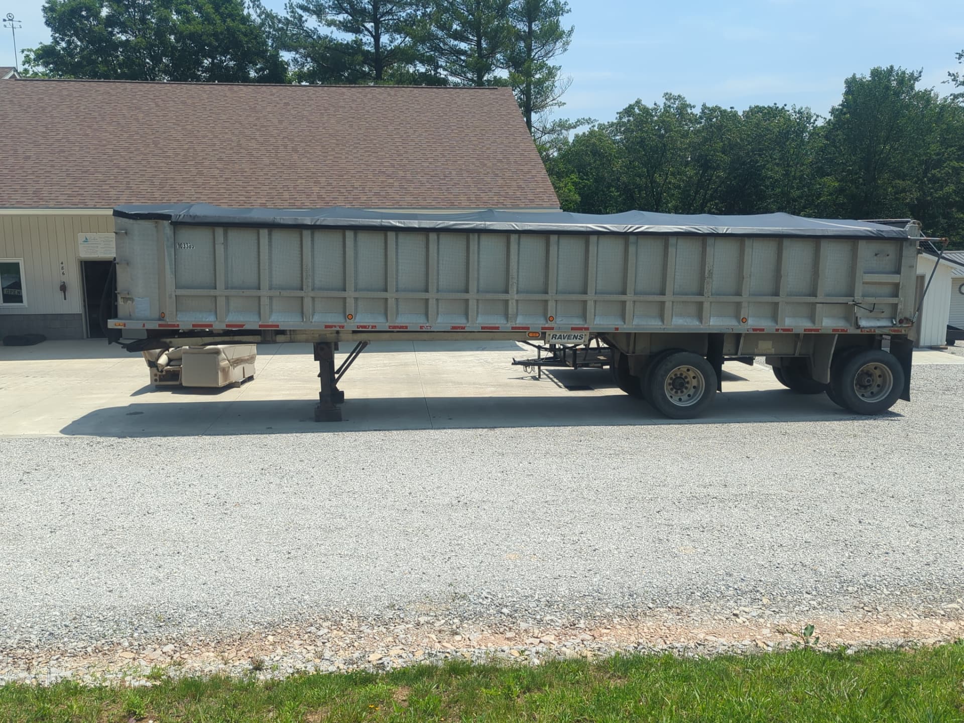 Dump trailer protected by a fitted gray tarp from Erbco